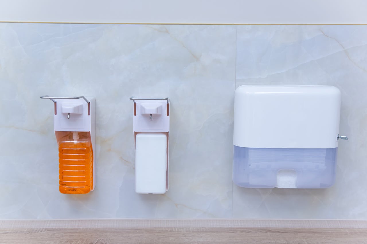 about-01 Close-up of wall-mounted soap, sanitizer, and paper dispenser in a sterile environment.